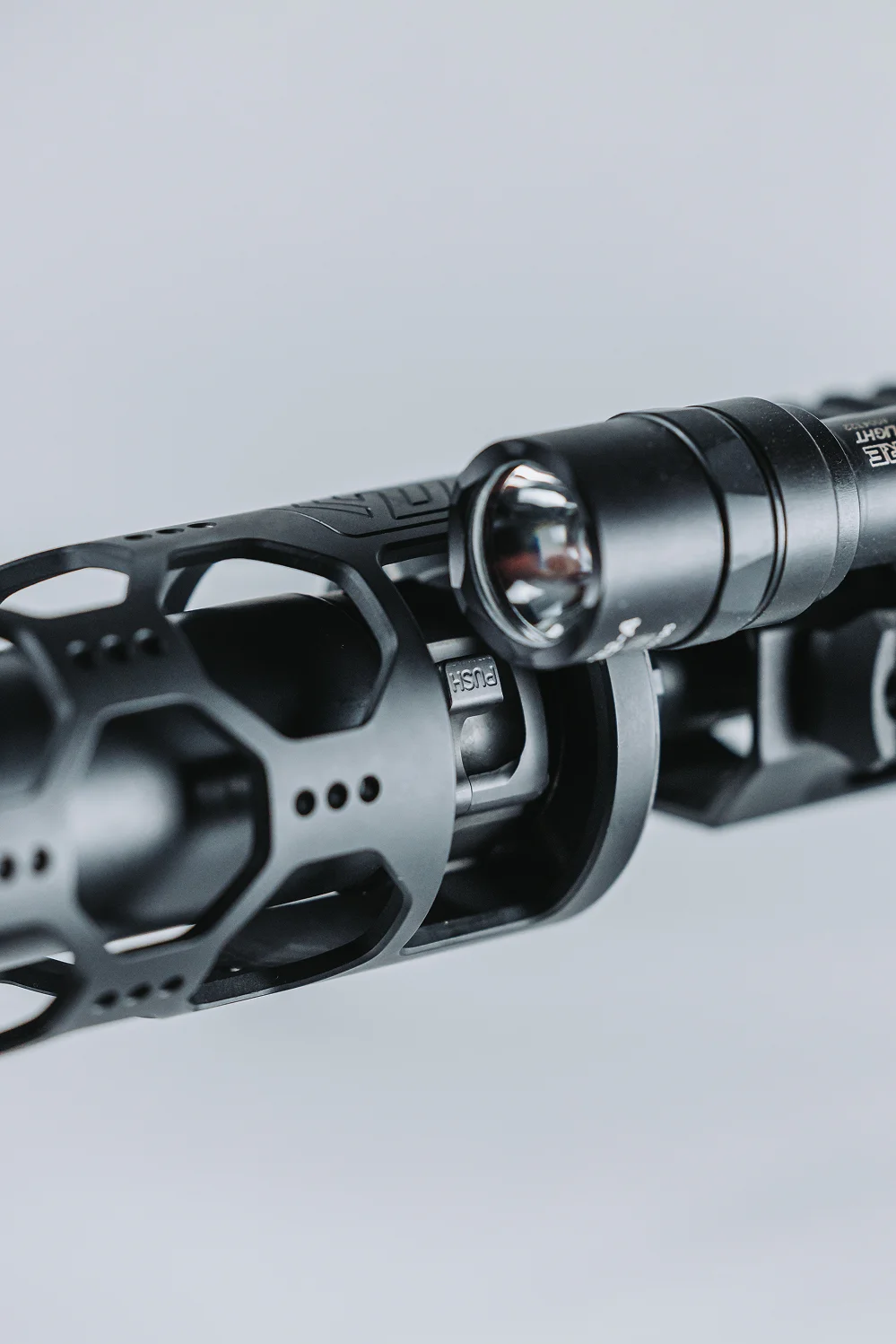 Close-up of a rifle equipped with a tactical flashlight, highlighting its features and functionality.