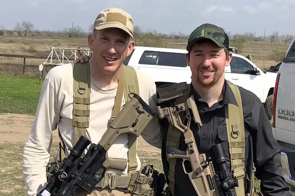 Two men dressed in military uniforms pose together for a photograph, showcasing their gear and camaraderie.