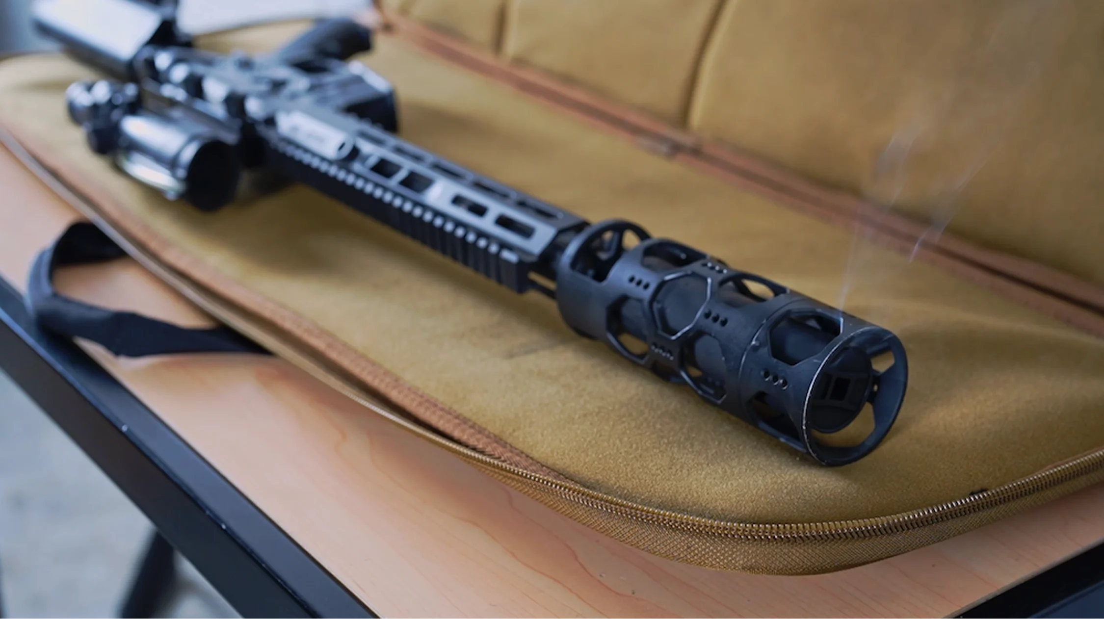 A rifle rests on a bag placed on a table, showcasing a combination of outdoor gear and equipment.